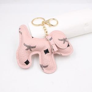 Pink dog-shaped keychain with black details on a white background
