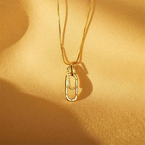 Gold necklace with a pendant on a yellow fabric background