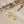 Gold hoop earrings with lightning bolt charms on a beige background with dried lavender.