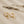 Gold hoop earrings with lightning bolt charms on a beige background with dried lavender.
