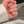 Hand wearing multiple gold necklaces and rings on a neutral background