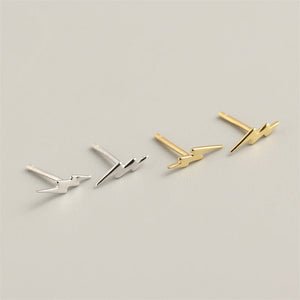A set of sterling silver stud earrings with a lightning bolt design, displayed on a black surface.