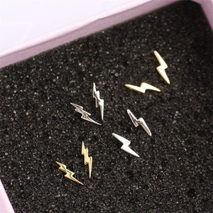 Gold and silver lightning bolt earrings on a black textured surface