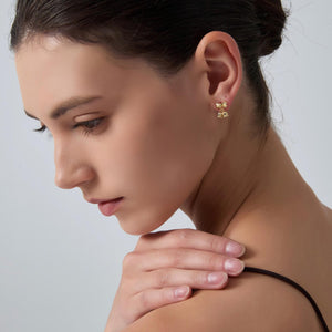 Close-up of a woman wearing gold earrings with a neutral background