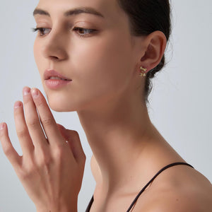 Close-up of a woman wearing gold earrings with a neutral background
