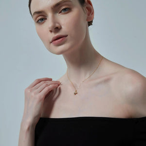 Woman wearing a delicate gold necklace against a plain background