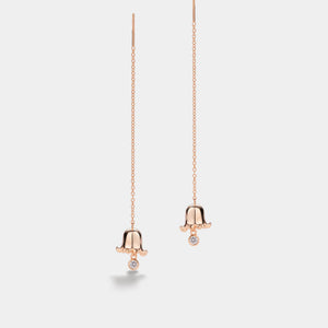 Rose gold bell-shaped earrings on a light gray background