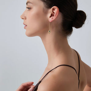 Woman wearing a gold earring against a plain background