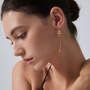 Close-up of a woman wearing gold earrings against a neutral background