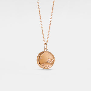 Rose gold necklace with a round locket featuring a fox and stars on a light gray background, inspired by 'The Little Prince'.