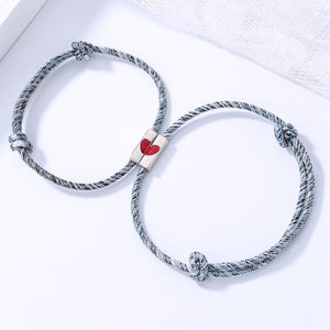 Two braided bracelets with a red heart charm on a white background
