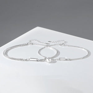 Silver bracelet on a white surface with a gray background