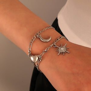 Silver bracelet with moon, heart, and star charms on a wrist against a neutral background