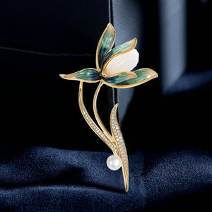 Floral brooch with green leaves and white flowers on a dark blue background