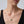 Gold necklace with a green pendant on a model against a neutral background