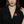 Woman wearing a black blazer with a red maple leaf brooch against a dark background