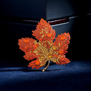 Maple leaf brooch with orange gemstones on a dark background