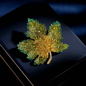 Gold and green leaf-shaped brooch on a dark surface