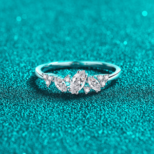 Silver ring with marquise-shaped diamonds on a teal textured background