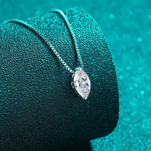 Silver necklace with a teardrop-shaped pendant on a textured green surface