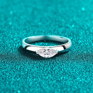 Silver ring with a heart-shaped diamond on a teal textured background