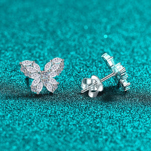 Butterfly-shaped silver earrings on a teal glittery background