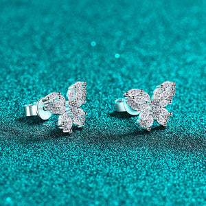 Butterfly-shaped earrings on a teal glittery background