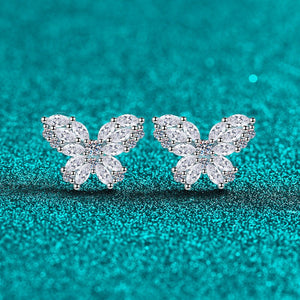 Butterfly-shaped earrings with clear gemstones on a teal background