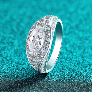 Silver ring with a large central moissanite on a turquoise glittery background