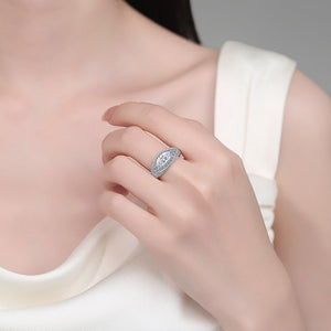Close-up of a hand wearing a silver ring with a moissanite, against a neutral background