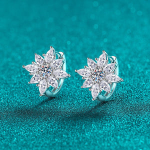 Pair of silver flower-shaped earrings on a teal background
