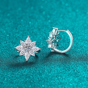 Silver star-shaped earring and hoop earring on a teal background