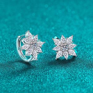 Silver flower-shaped earrings on a teal background