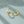 Gold hoop earrings with embedded stones on a light green fabric background
