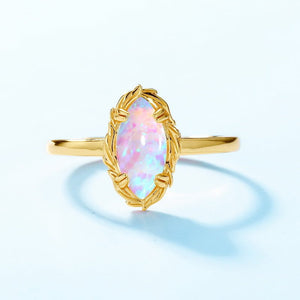 Gold ring with a pink opal stone on a light blue background