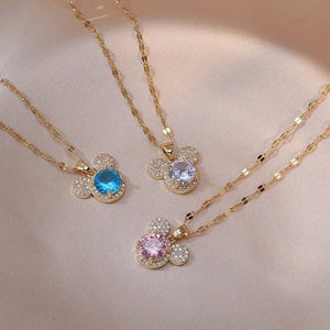 Three gold necklaces with colorful gemstone pendants on a beige background