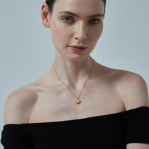 Woman wearing a gold necklace against a plain background