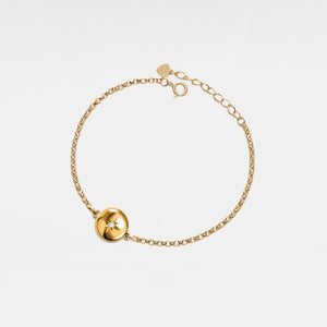 Gold bracelet with a round locket featuring a star design on a light gray background