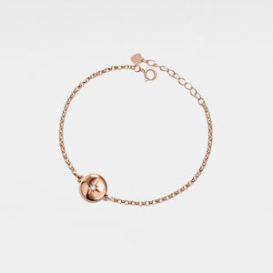 Rose gold bracelet with a round locket featuring a star design on a light gray background