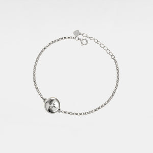 Silver bracelet with a round locket featuring a star design on a light gray background
