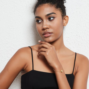 A model wearing a bracelet with a round locket featuring a star design on a light gray background
