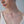 Close-up of a woman wearing a delicate necklace with a small star locket pendant on a plain background