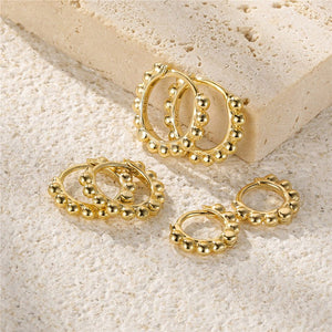 Gold hoop earrings on a textured beige surface