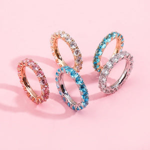 Four rings with different colored gemstones on a pink background