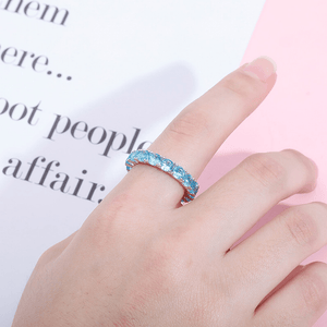Hand wearing a blue ring with a blurred text background
