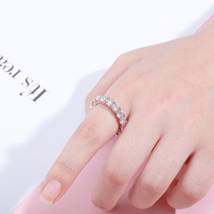 Rose gold ring with diamonds on a hand against a white background