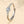 A silver wedding ring with a central cubic zirconia surrounded by smaller clear crystals, held by a shadow on a beige background.