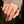 Gold snake-shaped ring on a person's finger with a blurred natural background