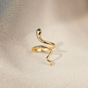 Gold snake-shaped ring on a beige fabric background
