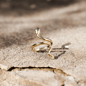 Gold snake-shaped ring on a sandy surface